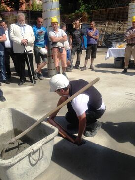 Ein Bauarbeiter legt die Zeitkapsel in den Grundstein der neuen Mittelpunktbibliothek Treptow.